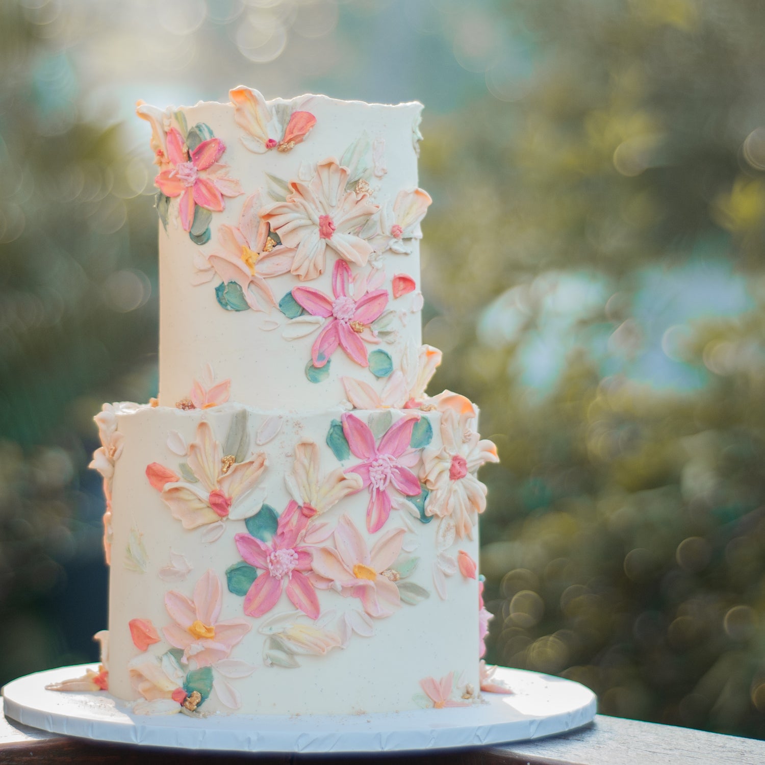 Two-tier buttercream wedding cake featuring a hand-painted palette knife floral design in pastel shades of pink, peach, and green, crafted for Brisbane weddings by Caldera.CAKING.