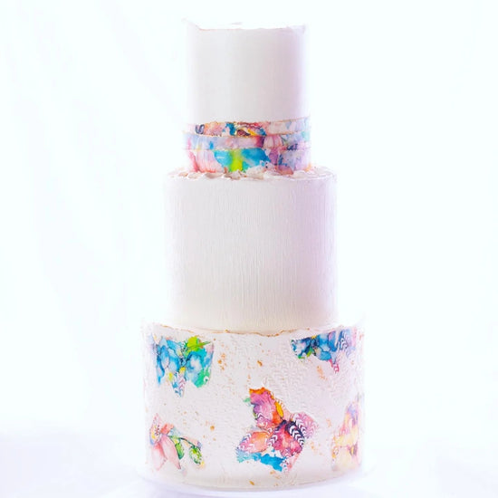 Three-tier wedding cake featuring smooth buttercream and vibrant wafer paper accents, designed for artistic Brisbane weddings by Caldera.CAKING.